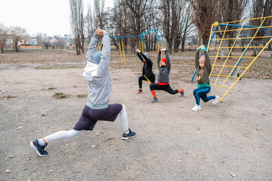 Group Fitness Workout Classes Outdoors. Socially Distant Outdoor Workout Classes In Public Parks. Three Women And Man Training Together In The Public Park. Health, Wellness And Community Concept