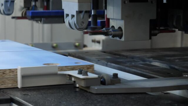 Machine for making holes and cutting parts from MDF. Manufacture of elements for furniture. Industrial equipment automated machine tool at a furniture manufacturing plant close-up