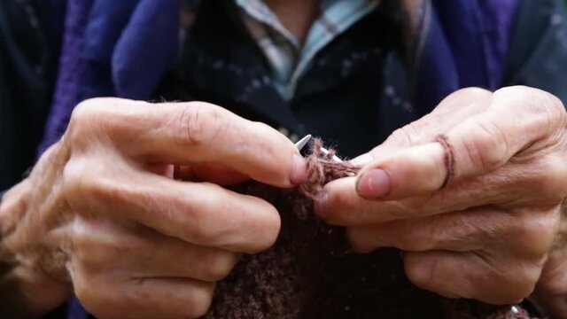 Close Up on old woman's hands knitting a sweater