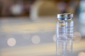 Close up photo of corona vaccine vial with blur background and beautiful bouquet. Drug prepare for immunization againt covid 19 pandemic.Selective focus at medicine banner.Medical concept.