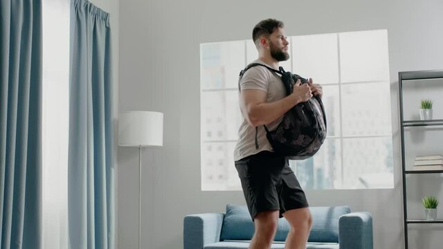 Concentrated guy practices squats with weight in backpack