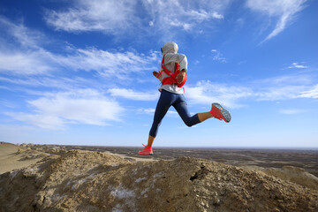 Woman trail runner cross country running  on sand desert dunes