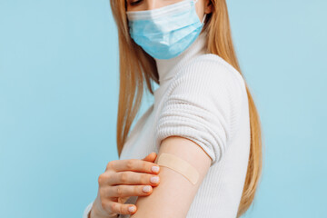 young woman in mask vaccinated, immunity, blue background, recommended vaccination, vaccination
