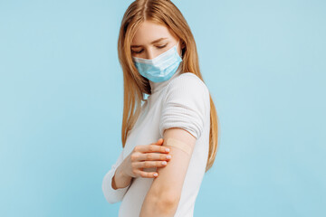 young woman in mask vaccinated, immunity, blue background, recommended vaccination, vaccination