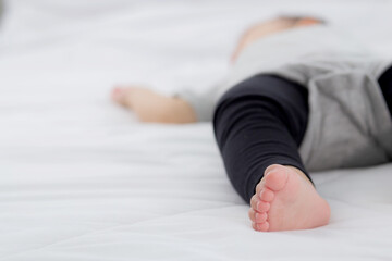 Fototapeta premium Closeup foot of asian little baby girl sleeping on bed in the bedroom at home, newborn napping with cozy and relax, infant innocence in bedtime, happy toddler cute, growth of child and emotion.