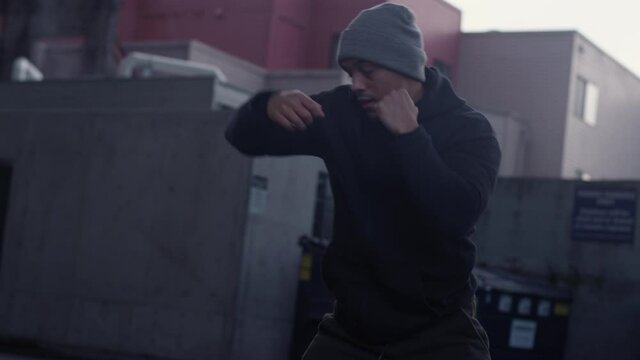 Slow motion shot of handsome Latino athlete shadowboxing under a bridge