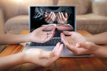 Close up hands of christian praying with computer laptop, Online live church for sunday service, Home church during quarantine coronavirus Covid-19