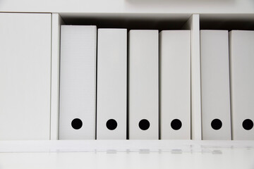 White folders with documents in a white shelf