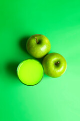 Top view of  apple juice with apples on green background. Healthy drink concept.