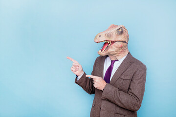 Euphoric man with lizard head pointing to the side on blue background.