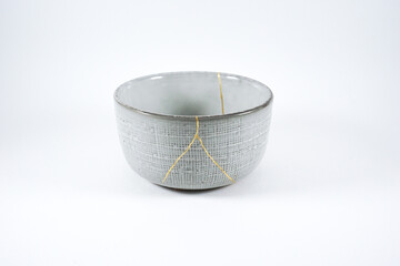 Grey broken pottery restored with Kintsugi, representation of broken heart with pottery.