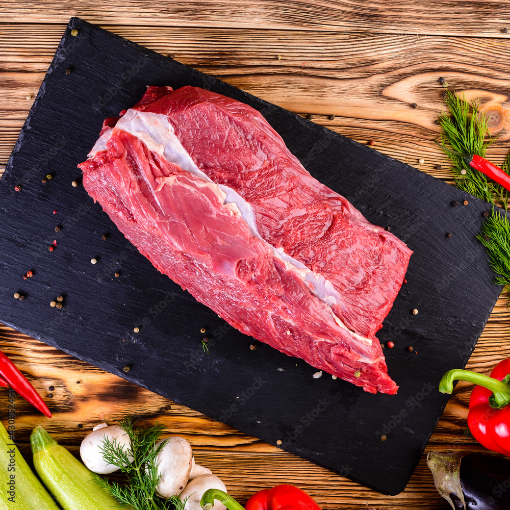 Wall mural raw fresh meat ribeye steak on slate dark wooden background