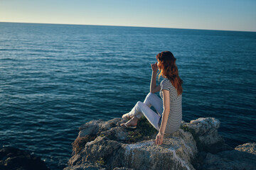 happy woman on a rock near the sea sunset blue sky and clear water