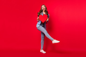 Full length body size view of attractive cheerful amazed girl holding heart shape dancing isolated over vivid red color background