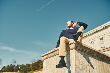 Outdoor portrait of handsome African American male model, posing against the sky, man fashion
