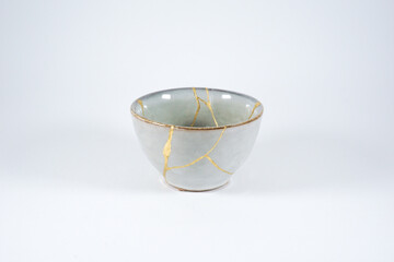 Grey broken pottery restored with Kintsugi, representation of broken heart with pottery.