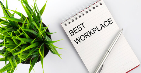 Keyword BEST WORKPLACE - business concept text on a white notebook and pen, green flowers