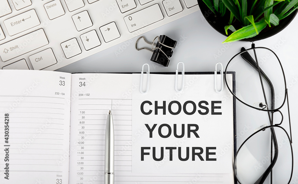 Aufkleber text choose your future on white stickers on the notebook with keyboard and glasses.