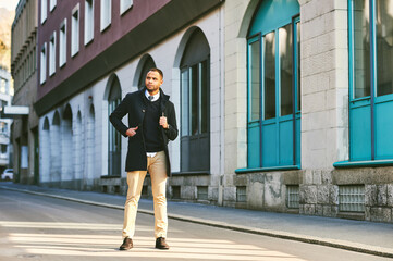 Urban portrait of handsome African American male model, wearing blue coat, posing outside