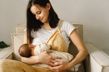 Newborn baby boy sucking milk from mothers breast. Portrait of mom and breastfeeding baby.