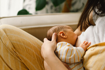 Newborn baby boy sucking milk from mothers breast. Portrait of mom and breastfeeding baby.