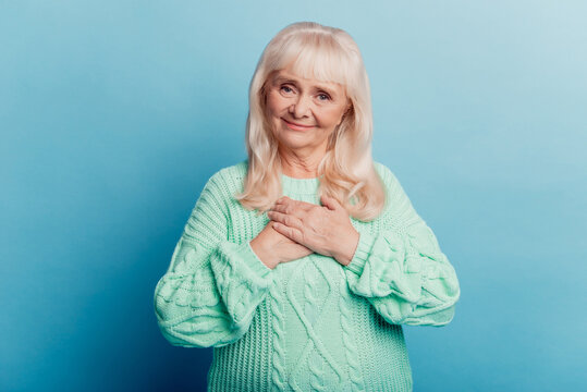 Peaceful old woman put hands chest isolated over blue background