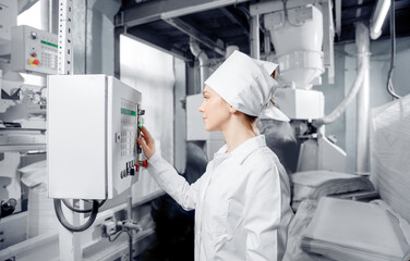 Factory engineer woman operating machine control panel in mill flour, milk food production plant....