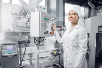 Factory engineer woman operating machine control panel in mill flour, milk food production plant
