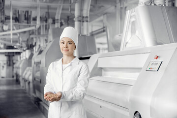 Plant operator engineer flour mill on background of modern equipment, woman holds wheat grain in hands