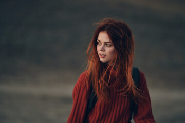 pretty woman in a sweater with a backpack are walking in nature in the mountains on a meadow