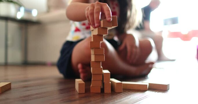 Little girl playing with building wooden blocks at home