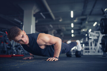 Fototapeta na wymiar Young athletic man doing push-ups in gym. Muscular and strong gu