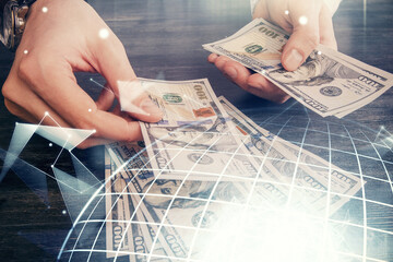 Double exposure of world map drawing hologram and us dollars bills and man hands.