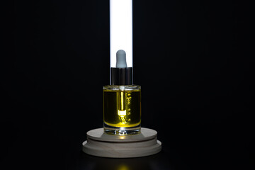 Face oil on a wooden podium with tube light behind lighting the dropper. Front view