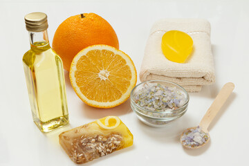 Cut orange with whole one, towel, bottle with aromatherapy oil and sea salt