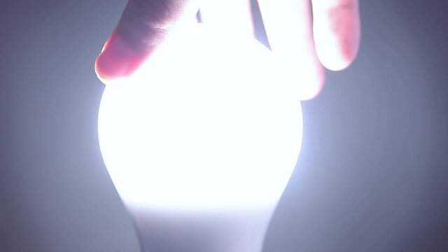 Man Rotates with His Hand a Led Bulb in Its Electrical Socket. Energy-saving, eco-friendly Led bulb lamp lights up