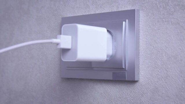 Hand plug or unplug  black power cord cable mobile phone charger charts Into electric socket on wall. Ready to connect plugging electrical. power saving or cost reduction concept.
