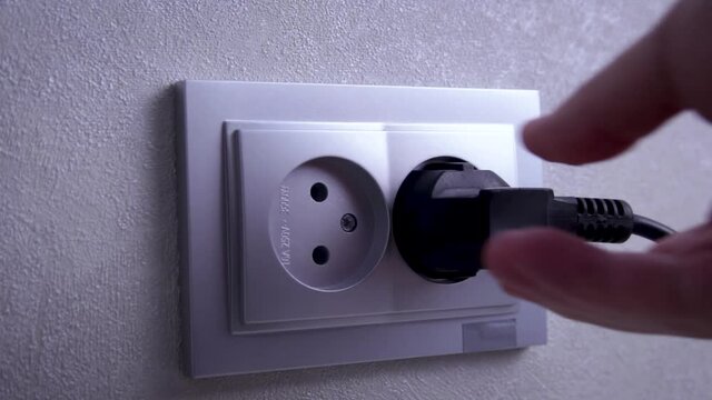 Socket with electric plug in the wall. Ready to connect. Plugging electrical, black plug in electric socket on wall.  The concept of energy savings.