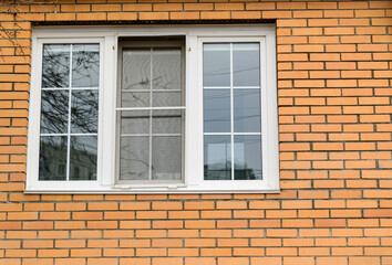 Brick wall with a window. Glare in the glass. House facade concept.
