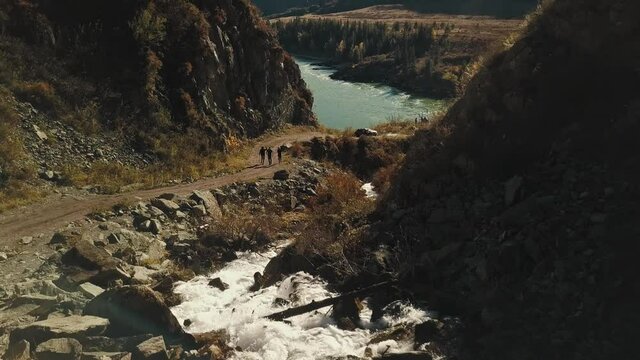 Aerial view of the calm mountain river Katun. Autumn landscape of the wild nature of the Altai Territory: Mountains, forests, fields, a country walking road, a mountain stream, the rays of the sun