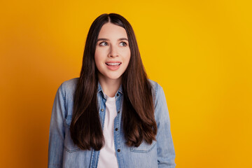 Fototapeta premium Portrait of happy excited girl look up empty space on yellow wall