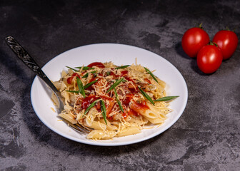 Penne pasta with tomatoes, sauce, cheese and Provencal herbs. Dark background. Space for copying. Top view. Penne pasta in tomato sauce - Italian food style