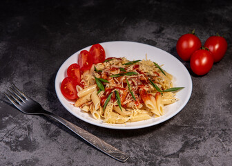 Penne pasta with tomatoes, sauce, cheese and Provencal herbs. Dark background. Space for copying. Top view. Penne pasta in tomato sauce - Italian food style