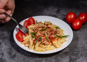 Penne pasta with tomatoes, sauce, cheese and Provencal herbs. Dark background. Space for copying. Top view. Penne pasta in tomato sauce - Italian food style