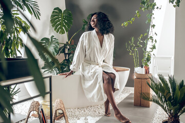 African american prety woman in a white robe in a bathroom
