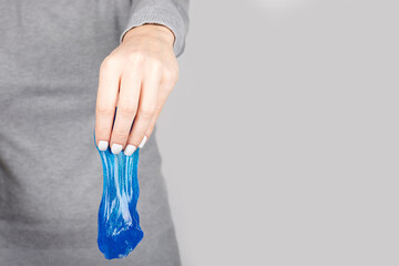 Hand with blue slime toy on grey background