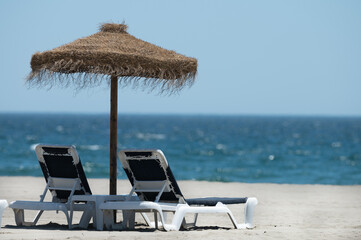 tumbona bajo sombrilla frente al mar bajo un cielo azul

