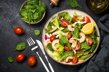 Shrimp salad with green leaves at stone table.