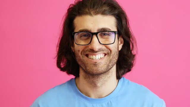 A Portrait Of A Smiling Man With Glasses Standing In A Pink Studio