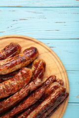 Grilled sausages on wooden board on blue background. Vertical photo